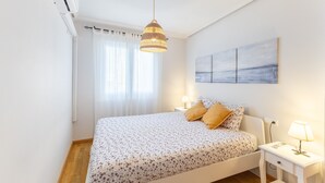 Une chambre à coucher avec un lit, des tables de chevet, une lampe suspendue et un tableau mural.