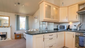 A kitchen with light wood cabinets, a granite countertop, a microwave, and a stove. - 1 Ocean Terrace (Ilfracombe)