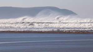 A beach with waves crashing onto the shore and a distant mountain range. - 1 Ocean Terrace (Ilfracombe)