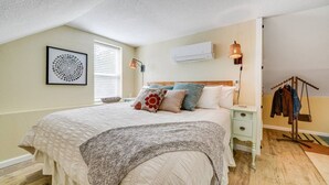 Ein Schlafzimmer mit Bett, Nachttisch, Lampe und einer Kleiderstange.