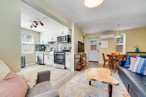 A compact living space with a kitchenette, a dining area, and a seating area with a sofa and a coffee table.