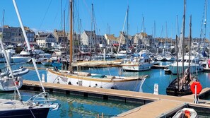 A marina with numerous boats docked, a wooden pier, and buildings in the background. - Modern 1-bedroom with sea view, Tatihou Island, balcony, Wi-Fi, garage, near port and center (Saint-Vaast-la-Hougue)
