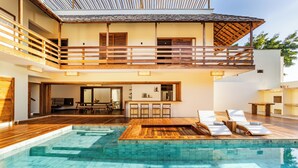 A two-story building with a wooden deck, a swimming pool, and a balcony.