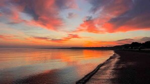 A beach at sunset with calm waters reflecting the sky.