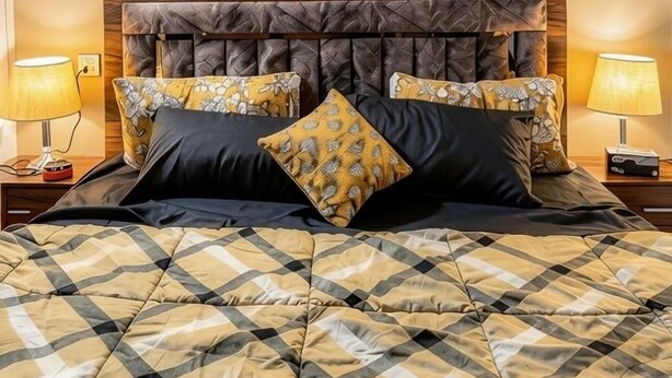 A bed with a quilted cover, two framed horse paintings on the wall, and bedside lamps.