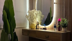 A bathroom with a wooden vanity, a mirror with a light, and a potted plant.