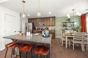 A modern kitchen with granite countertops, stainless steel appliances, and a central island with bar stools.