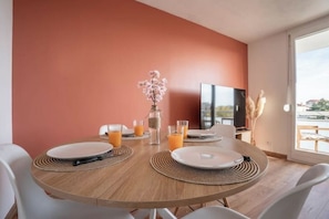 Een eethoek met een ronde tafel, witte stoelen en een bloemenvaas.