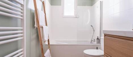 Un baño pequeño con bañera, inodoro y una escalera de madera apoyada en la pared.