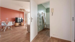 Amplia sala de estar con mesa de comedor, sillas, televisor de pantalla plana y un cuadro en la pared.