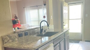 A kitchen with a granite countertop, a dishwasher, and a sink.