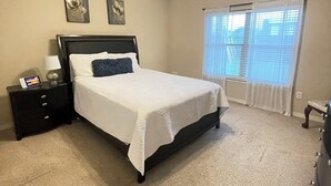 A bedroom with a bed, nightstand, lamp, ceiling fan, and window with blinds.