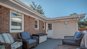 A covered patio with wicker furniture, a storage chest, and a door with a mailbox. - Coco Cottage: Dog-Friendly Bungalow in Quiet, Walkable Neighborhood (Oak Island)