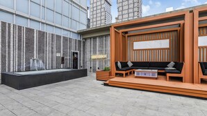 An outdoor seating area with a modern design, featuring a black sofa set and a wooden bench. - Executive 1BR at 300 Front St W | Balcony & Gym (Toronto)