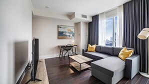 A modern living room with a grey sofa, wooden coffee table, and a flat-screen TV. - Executive 1BR at 300 Front St W | Balcony & Gym (Toronto)