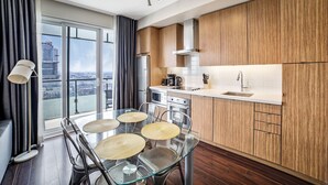 A modern kitchen with wooden cabinets, a glass dining table, and a city view. - Executive 1BR at 300 Front St W | Balcony & Gym (Toronto)