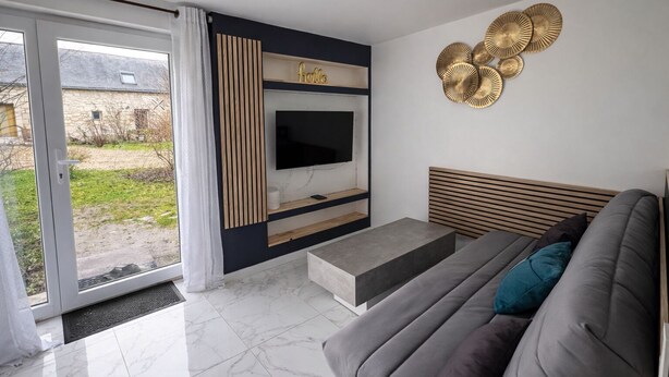 A modern living room with a sofa, TV, and decorative wall art. - Gîte Le Laurier (Villebernier)