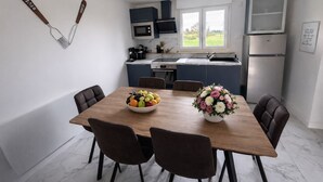 A modern kitchen with a dining table, chairs, a fruit bowl, and a flower arrangement. - Gîte Le Laurier (Villebernier)