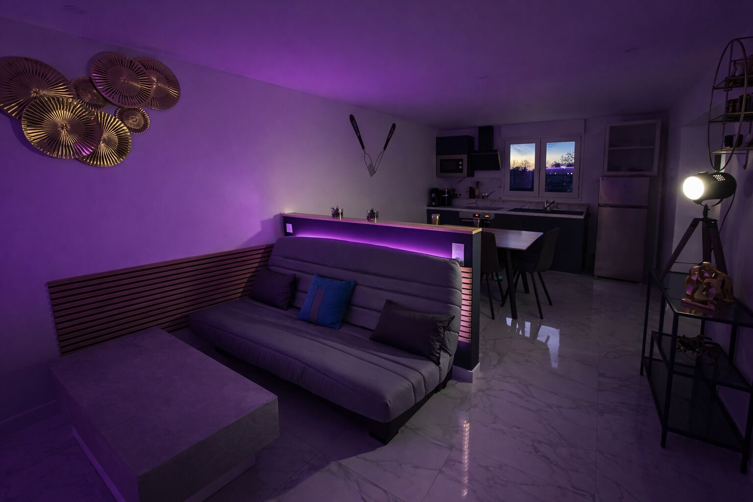 A modern living room with a sofa, a dining area, and a kitchen.