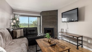 Un salon moderne avec un canapé, une table basse, une cheminée et un téléviseur fixé au mur.