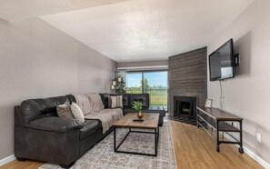 A modern living room with a leather sofa, a coffee table, a fireplace, and a mounted TV. - Amazing golf course and sunset views in Old Town Scottsdale (Scottsdale)