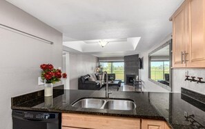 A modern kitchen with a central island, a built-in dishwasher, and a dining area with a sofa and table. - Amazing golf course and sunset views in Old Town Scottsdale (Scottsdale)