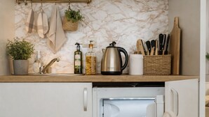 Cuina compacta amb nevera integrada, taulell de fusta i protecció de marbre.