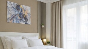 Un dormitori modern amb un llit gran, una taula de nit, una làmpada i una obra d'art penjada a la paret.