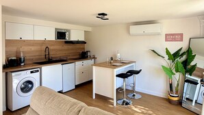 Un espacio habitable compacto con kitchenette, comedor y zona de estar con sofá.