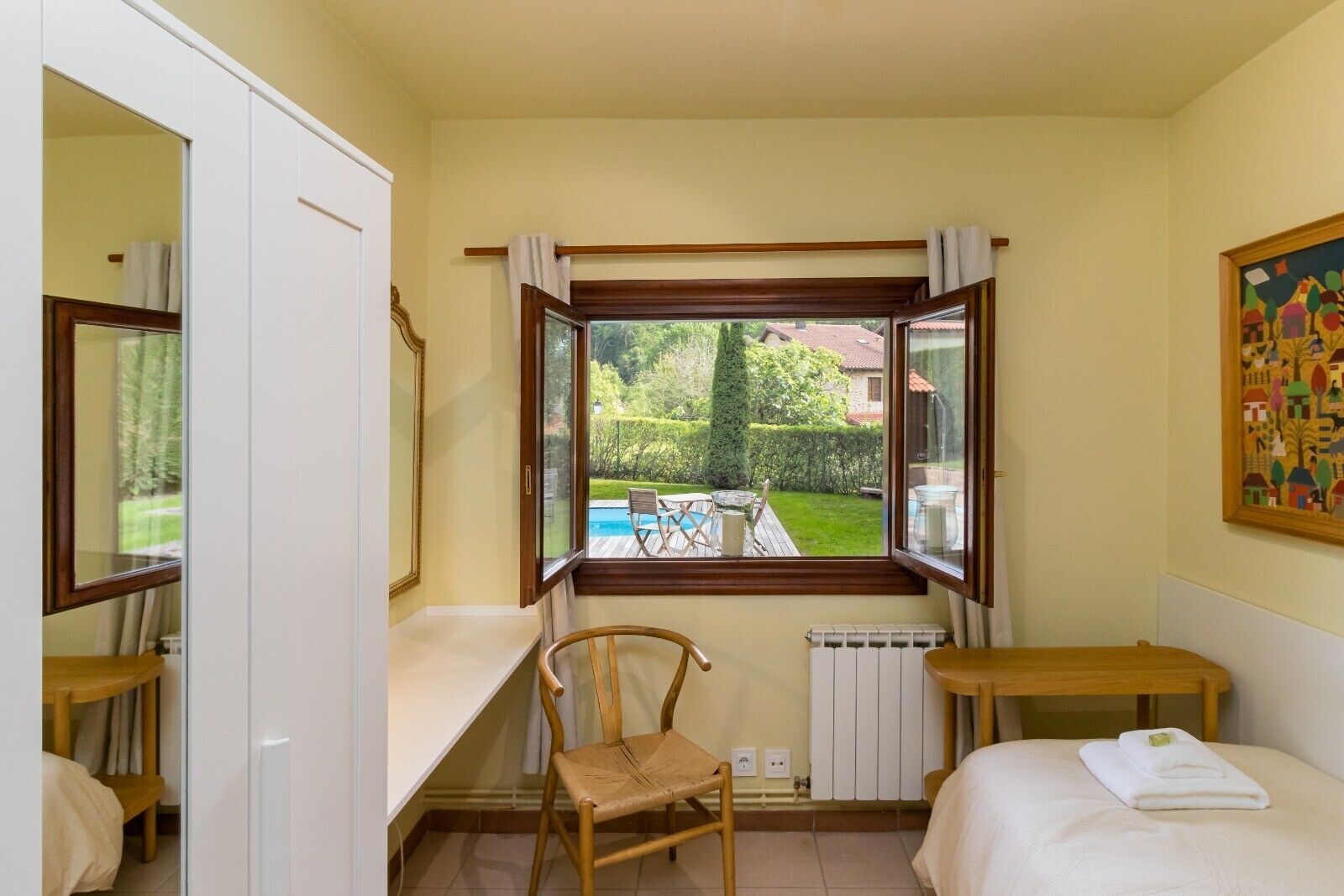 Una camera da letto con vista sulla piscina e sul giardino, una sedia, un letto e un tavolo.