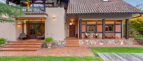 A two-story house with a patio area, a balcony, and a well-maintained lawn.