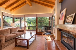 Un salón acogedor con chimenea, un sofá, una mesa de centro y un balcón con vistas al campo.
