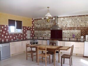A kitchen with a dining table, chairs, a built-in oven, and a stone backsplash.