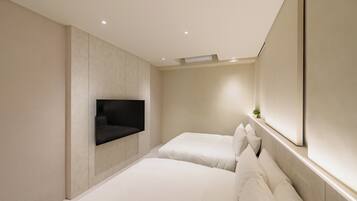 A modern hotel room with two beds, a large mirror, and a mounted TV.