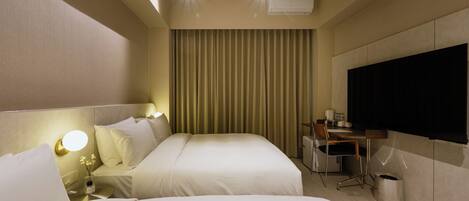 A hotel room with two beds, a desk, a chair, a TV, and a curtain.