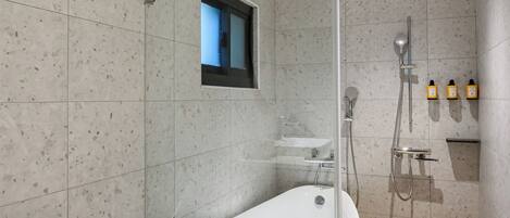 Un baño moderno con ducha envuelta en vidrio, una bañera independiente y un inodoro con panel de control.