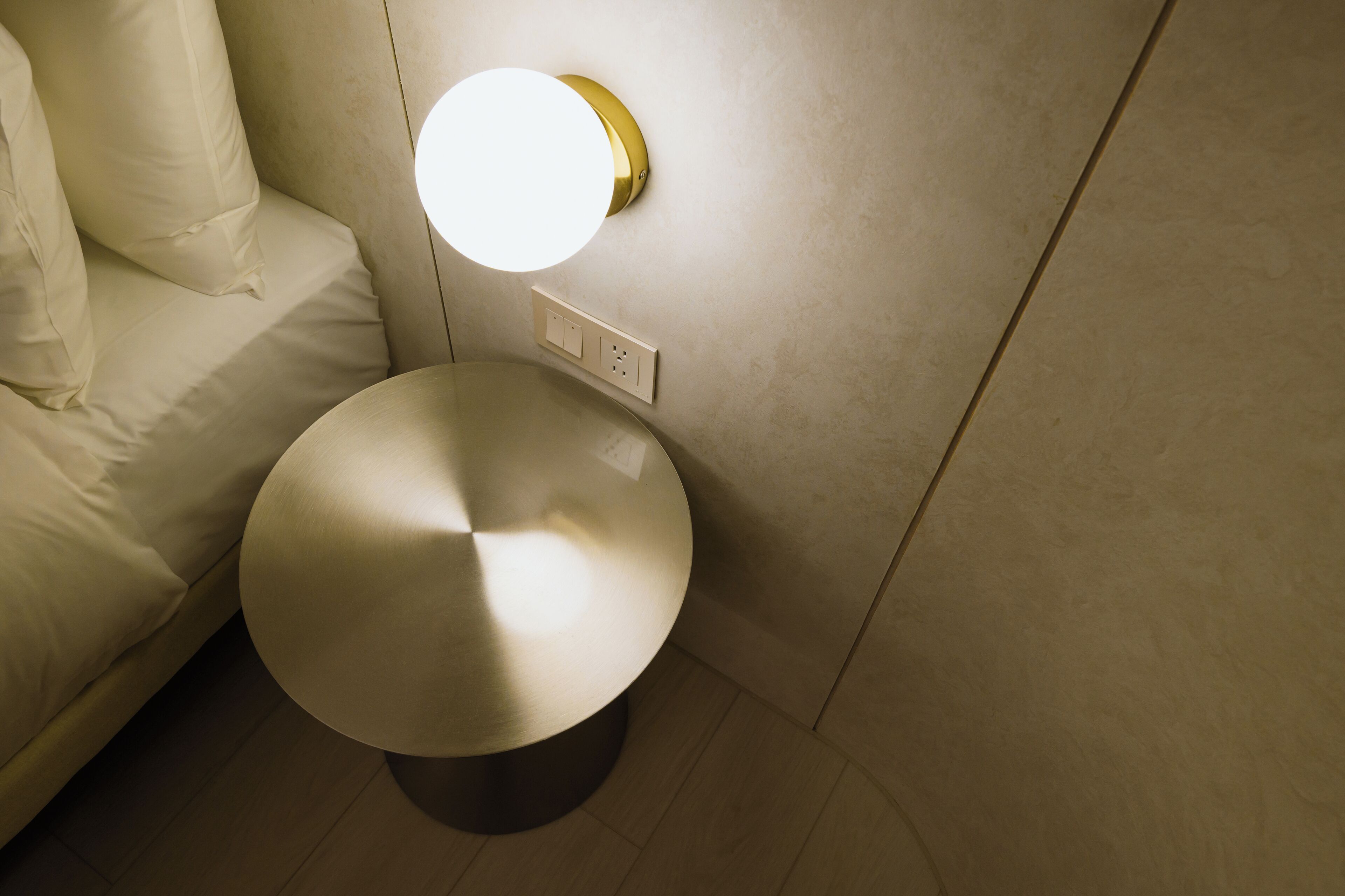 Un baño moderno con un espejo redondo, una lámpara de pared y un inodoro.