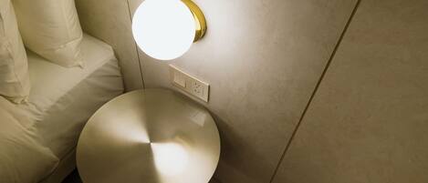 Un baño moderno con un espejo redondo, una lámpara de pared y un inodoro.