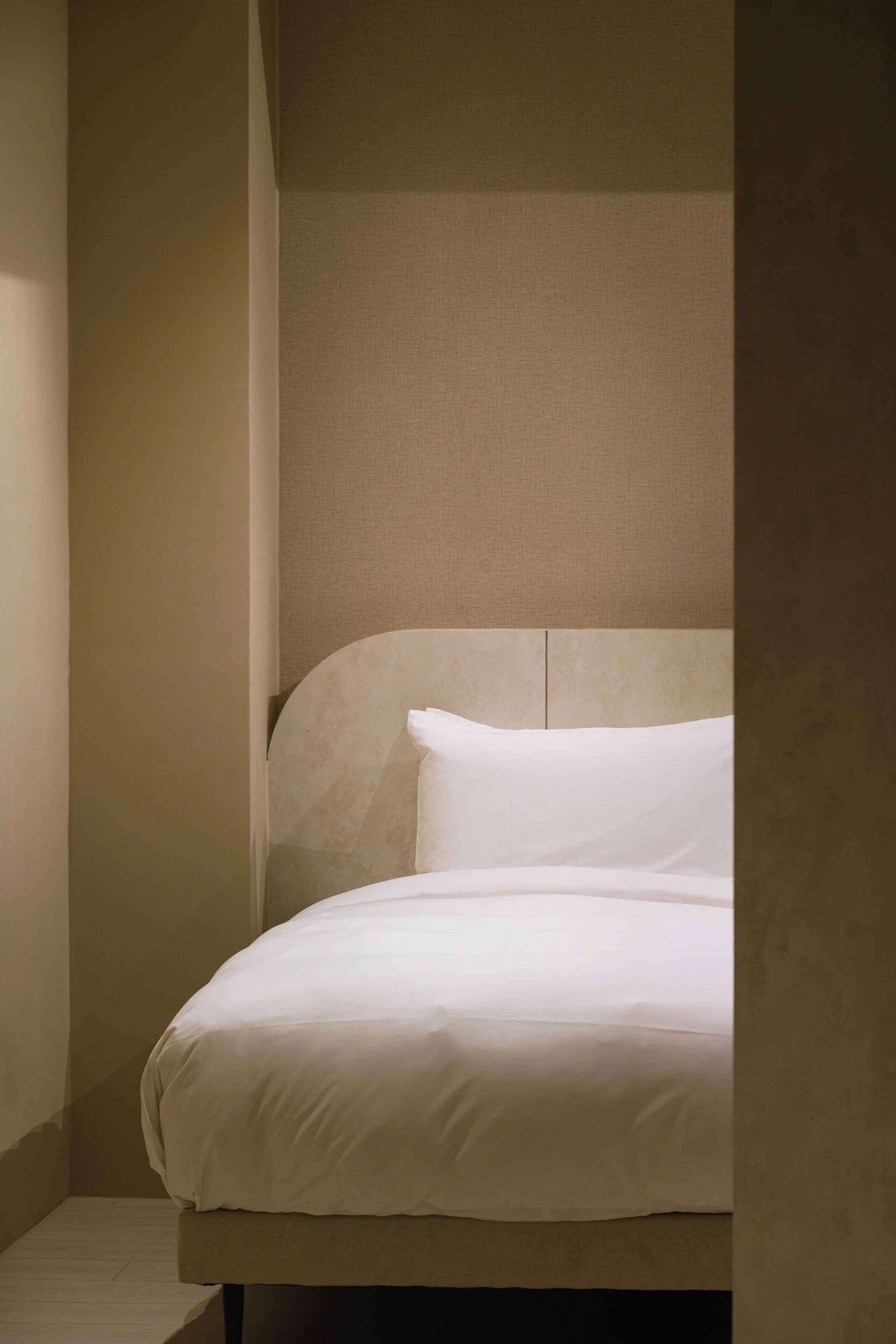 Un lit bien fait, avec une tête de lit, dans une chambre d’angle.