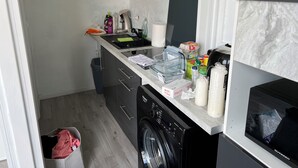 Ett kompakt kök med tvättmaskin, mikrovågsugn och diskho.