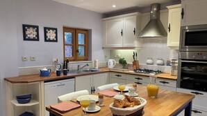 Eine moderne Küche mit weißen Schränken, einer Holzarbeitsplatte, einem Gasherd und einem eingebauten Backofen.