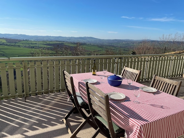 An outdoor dining area with a table set for two, overlooking a scenic landscape.
