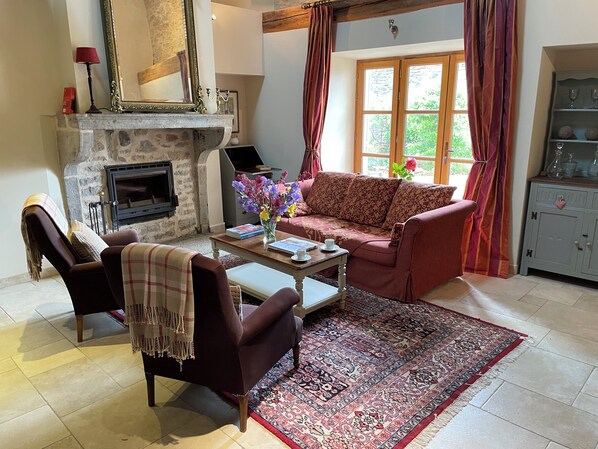 Un salon avec une cheminée, un canapé, des fauteuils, une table basse et un tapis.