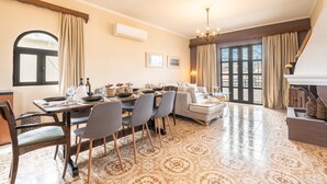 A dining area with a table set for four, a sofa, and a fireplace. - Apartment 'Afentika Grand Flat' with Mountain View, Wi-Fi and Air Conditioning (Archangelos)