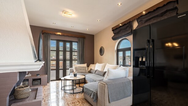 A modern living room with a sofa, coffee table, and a black refrigerator. - Apartment 'Afentika Grand Flat' with Mountain View, Wi-Fi and Air Conditioning (Archangelos)
