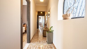 A hallway with patterned flooring, a potted plant, and a window with a view. - Apartment 'Afentika Grand Flat' with Mountain View, Wi-Fi and Air Conditioning (Archangelos)
