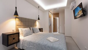 Ein modernes Schlafzimmer mit einem großen Bett, Nachttischen, einer Deckenleuchte und einem an der Wand montierten Fernseher.