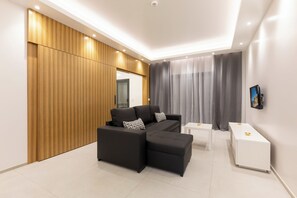 A modern living room with a sectional sofa, a white side table, and a wooden accent wall. - Correeira Luxury Residence A (Albufeira)