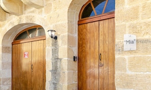 Deux portes en bois avec une pancarte indiquant « Garage », une fenêtre en arc de cercle et une autre pancarte sur laquelle on peut lire « Mia ».
