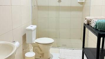 A small bathroom with a toilet, sink, and shower.